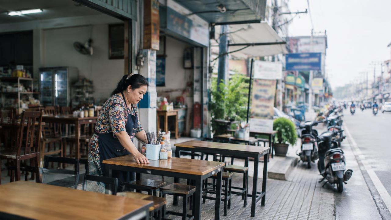 เจ้าของร้านอาหารจัดโต๊ะหน้าตึกแถวริมถนน ยามเช้า