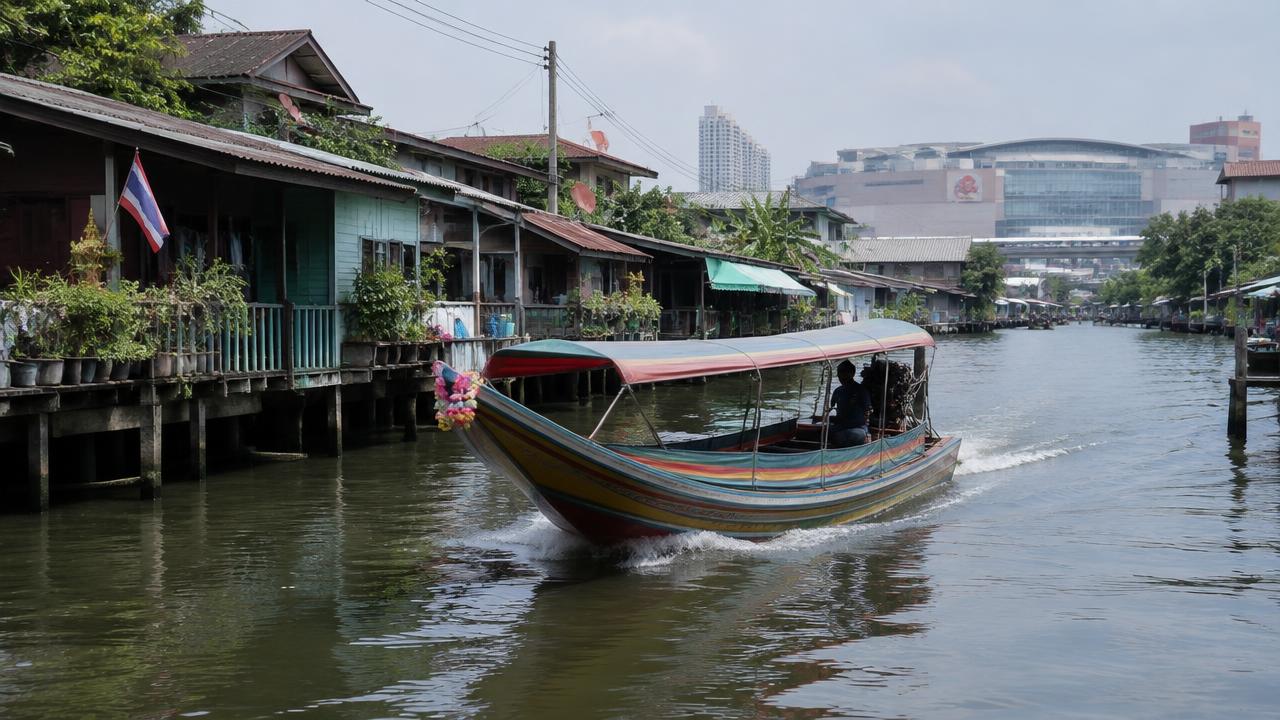 เรือหางยาววิ่งในคลองผ่านบ้านริมน้ำ มีห้างสรรพสินค้าอยู่ไกล ๆ